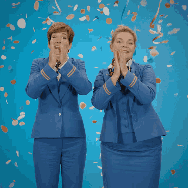 two women in blue uniforms are clapping while confetti is falling around them