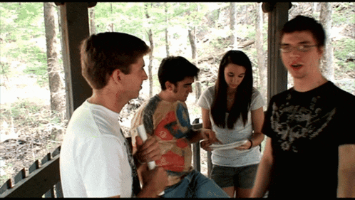 a group of people standing on a porch one of whom is wearing a shirt that says ' t.j. '