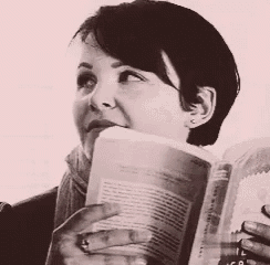 a woman with short hair is reading a book with a ring in her finger