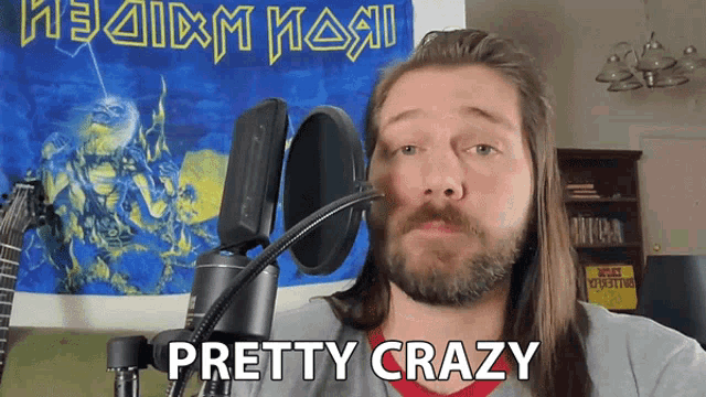 a man with long hair and a beard stands in front of a microphone and says " pretty crazy "