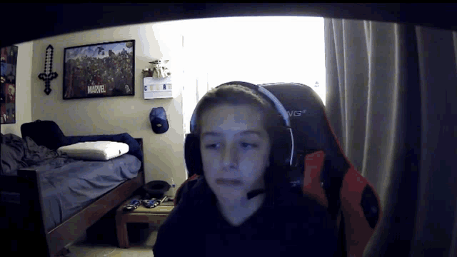 a boy wearing headphones is sitting in front of a marvel poster