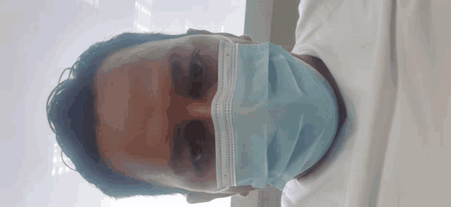 a man wearing a white shirt and a blue mask on his face