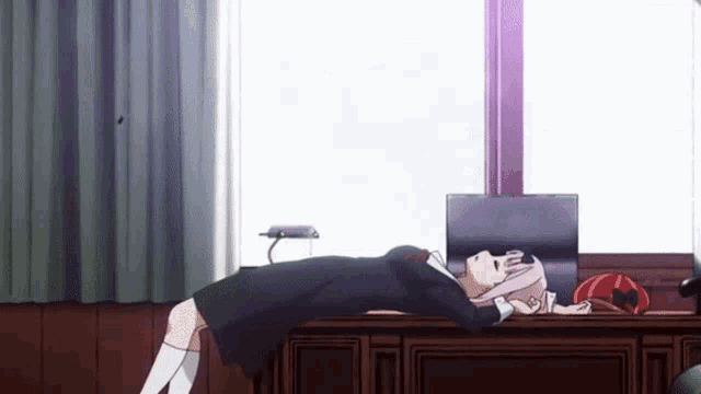a girl is laying on a desk in front of a window in a room .