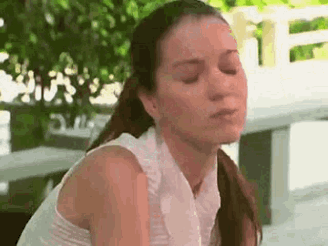 a woman is sitting on a bench with her eyes closed and her mouth open .