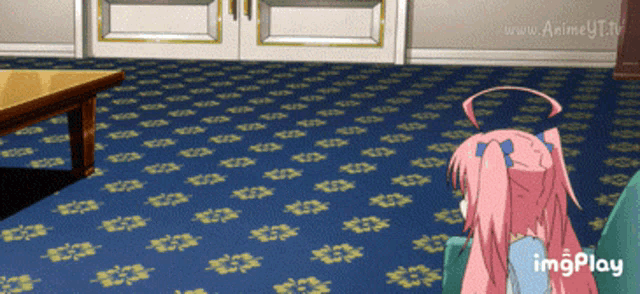 a girl with pink hair is sitting on a couch in a room with a blue carpet and a table