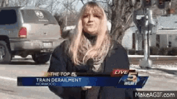 a woman is holding a microphone in front of a sign that says train derailment norwood