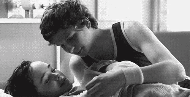 a black and white photo of a man and woman laying in bed .