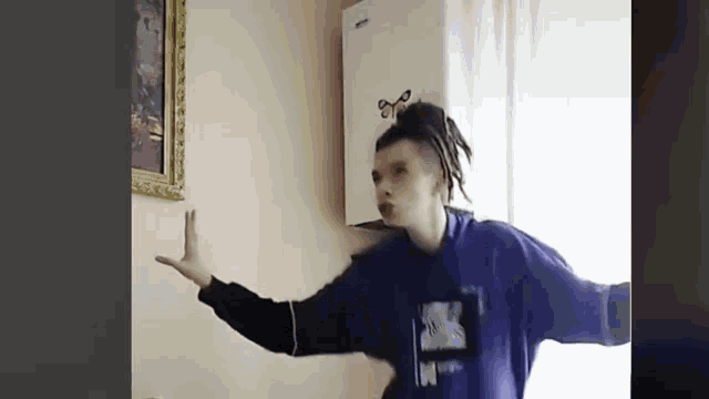 a man in a blue shirt is dancing in a room .