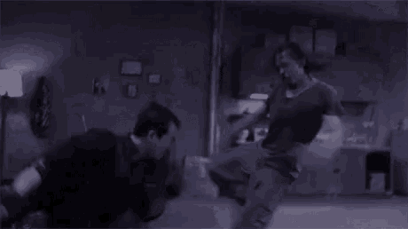 a man is laying on the ground in a dark room while another man is standing next to him .