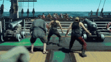 a group of men are dancing on the deck of a ship with cannons in the background