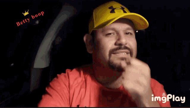 a man wearing a yellow under armour hat is eating