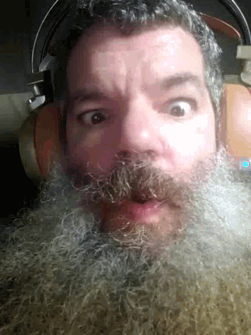 a man with a beard is wearing headphones and looking at the camera