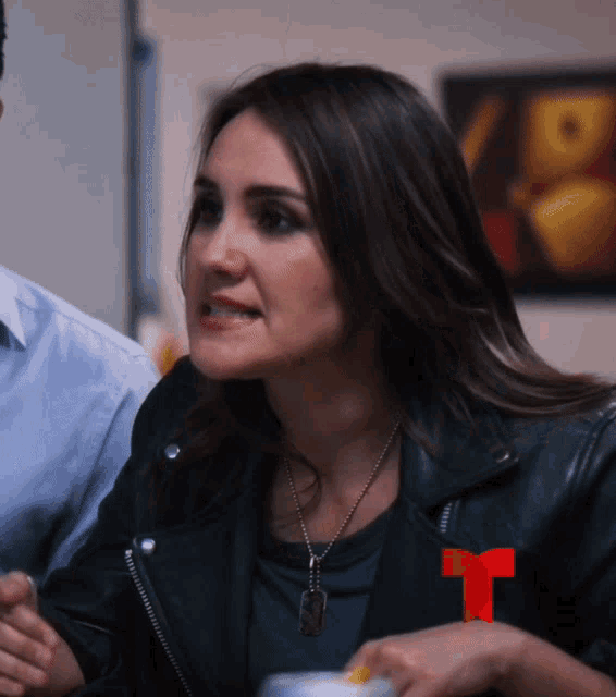 a woman wearing a black leather jacket has a red t on her sleeve
