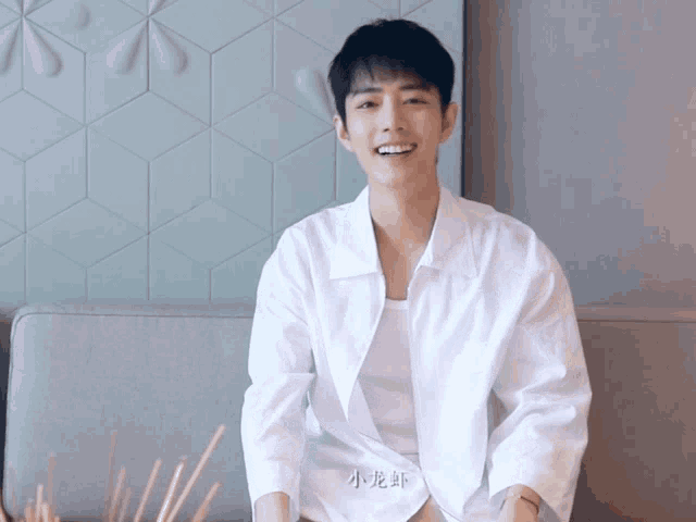 a man wearing a white shirt with chinese writing on it smiles