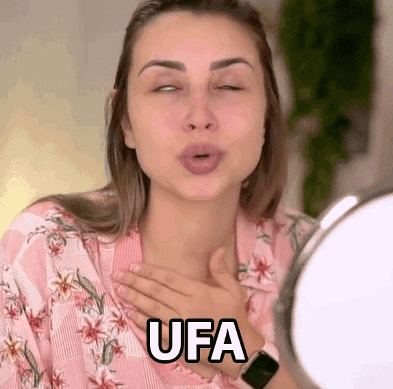 a woman is looking at herself in a mirror with the word ufa written on her chest
