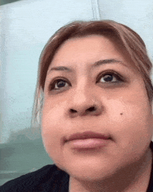 a close up of a woman 's face with a nose ring and a black shirt .