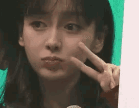 a young woman is making a peace sign with her fingers .