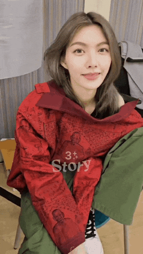 a woman is wearing a red jacket that says story on it