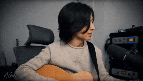 a man playing an acoustic guitar with the name agis on the bottom