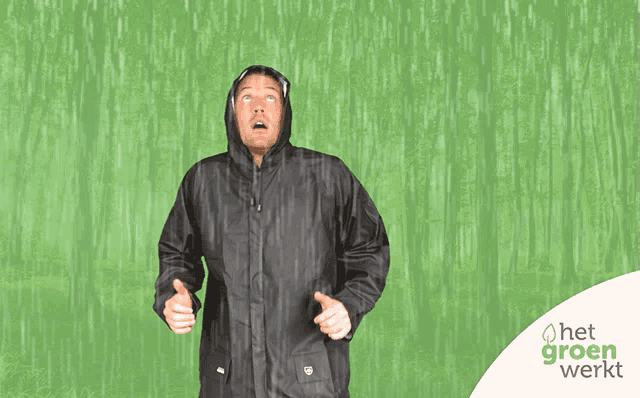 a man in a black raincoat is standing in the rain with the word het groen werkt in the corner
