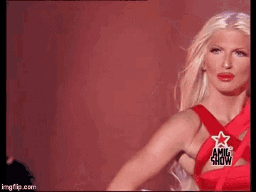 a blonde woman in a red dress with a star on the back is dancing on a stage .