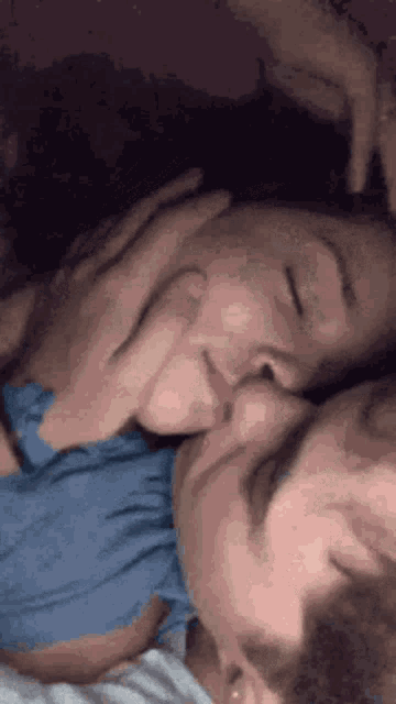 a man and a woman are kissing each other while laying in bed .