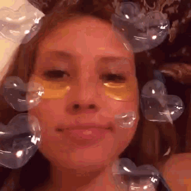 a close up of a woman 's face with heart shaped bubbles on her face .
