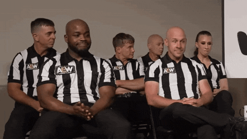a group of men wearing aew shirts sit in a row