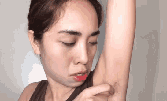 a woman is looking at her armpit with her eyes closed and a red lip .