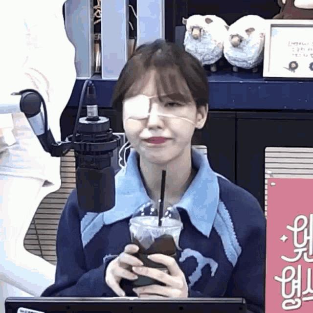 a girl with a bandage on her eye is holding a cup of coffee .