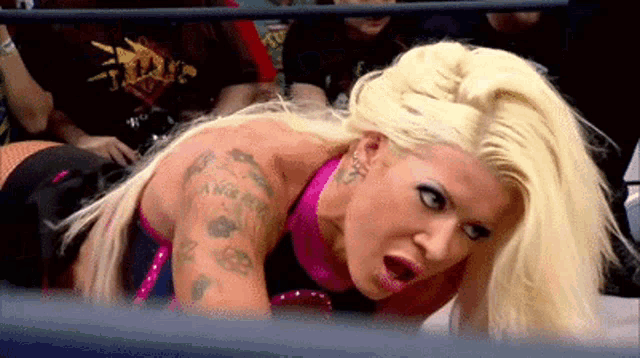 a woman with blonde hair and a tattoo on her arm that says angel