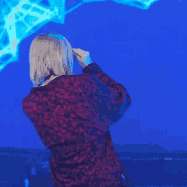 a woman in a red jacket stands in front of a blue screen