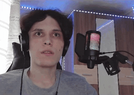 a young man wearing headphones and a microphone is sitting in front of a mirror .
