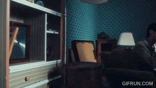 a man sits on a couch in a living room with a gif run.com watermark