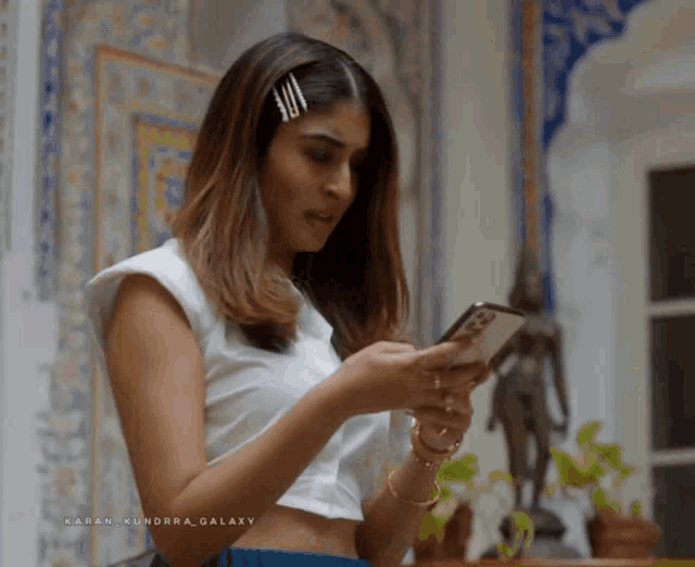 a woman in a white top is looking at her cell phone