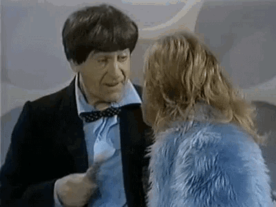 a man in a suit is talking to a woman in a fur coat .