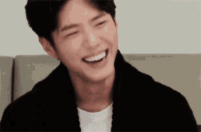 a young man is smiling with his eyes closed and his mouth open
