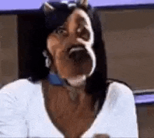 a woman with a big nose and horns is wearing a white shirt and making a funny face .