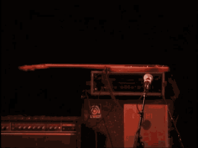 a man in a red shirt is playing a guitar in front of a microphone