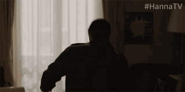 a silhouette of a man standing in a dark room with #hannatv written on the bottom