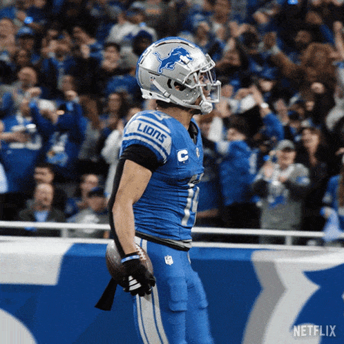 a football player for the detroit lions is holding a ball