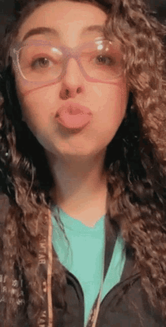 a woman with curly hair wearing glasses and a blue shirt