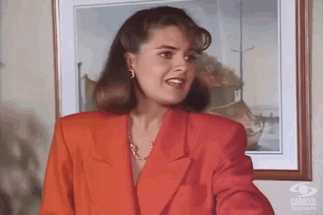 a woman in a red jacket is standing in front of a caracol television frame