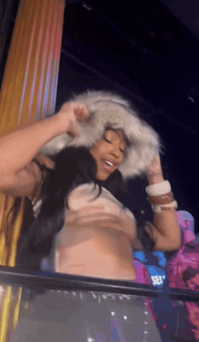 a woman wearing a fur hat and a crop top is standing in front of a window .