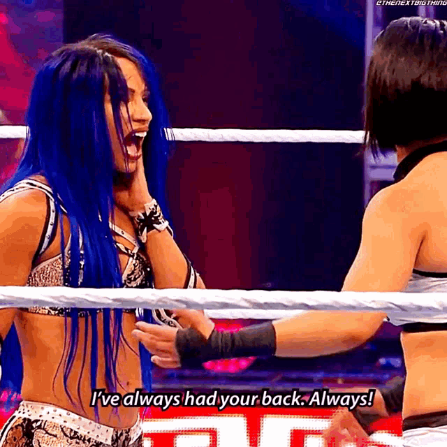 a woman with blue hair is talking to another woman in a wrestling ring