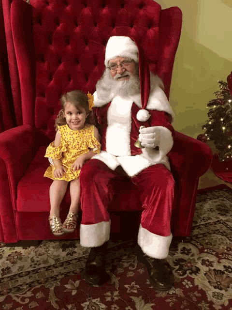 a little girl sits on santa 's lap in a chair