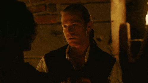 a man in a dark room drinking from a small bottle