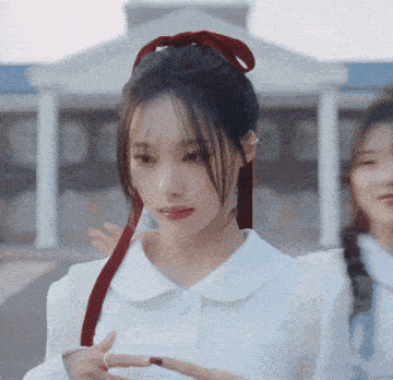 a girl with a red ribbon in her hair is standing in front of a building