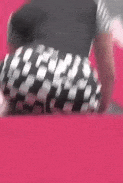 a woman in a black and white checkered skirt is dancing on a red surface .