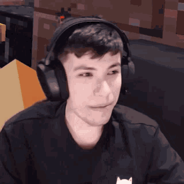 a young man wearing headphones is sitting in front of a computer screen .
